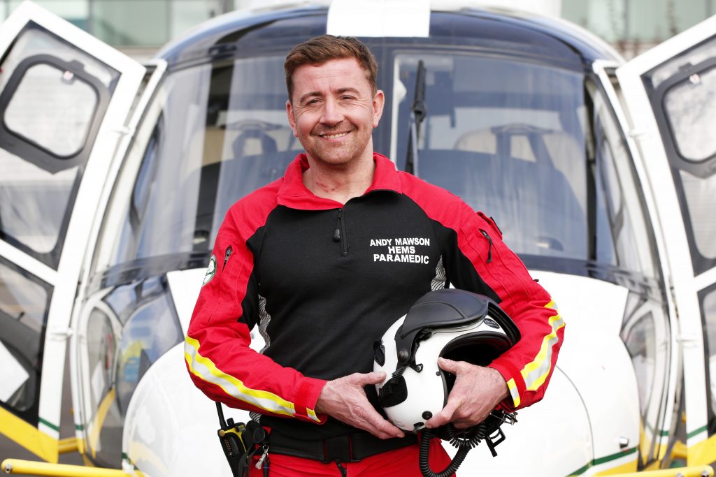 Paramedic smiling in front of the nose of a helicopter