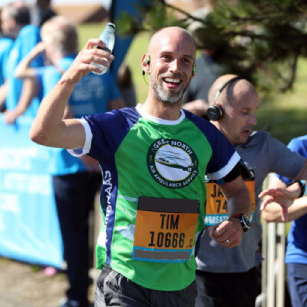 Man running a sponsored run for GNAAS, wearing a GNAAS running t-shirt.